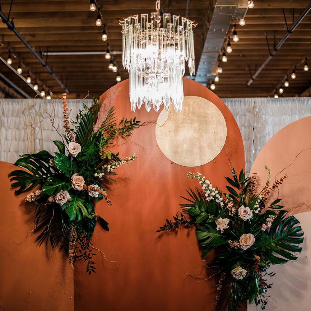 Ceremony backdrop with large tropical palms and floral focal points.